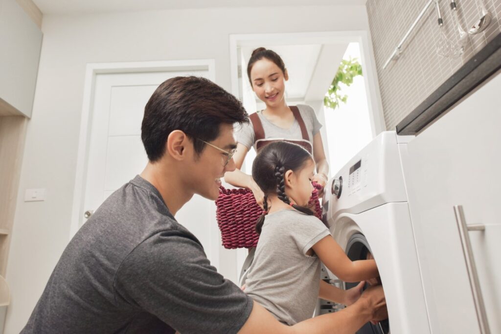 Happy Family loading clothes into Laundry machine