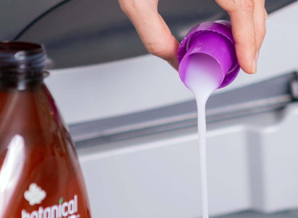 Hand pouring laundry detergent into washing machine