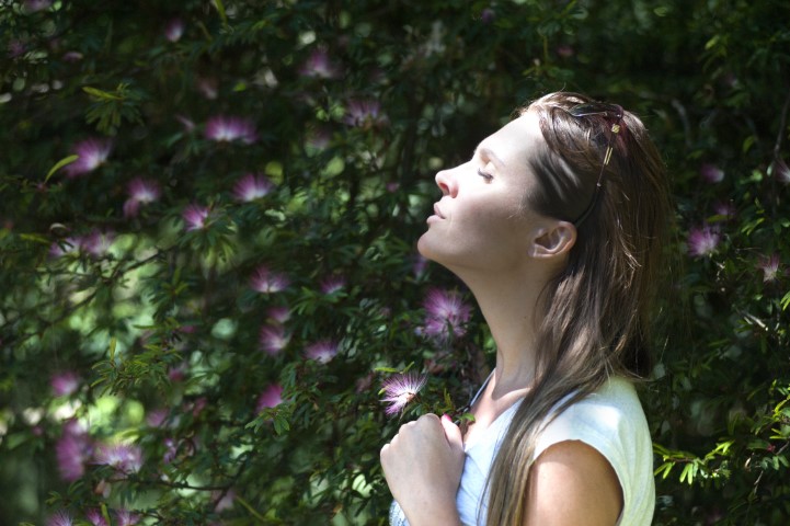 Woman taking a deep breath near flowers